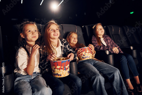 Relaxing and having fun. Group of kids sitting in cinema and watching movie together