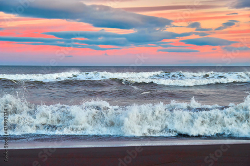 Fototapeta Naklejka Na Ścianę i Meble -  Evening restless sea. High waves on the evening beach, the rays of the setting sun.