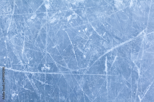 Empty ice rink with skate marks after the session outdoor. skating ice rink texture covered with snow in daylight. Close up of blue ice rink floor, copy space