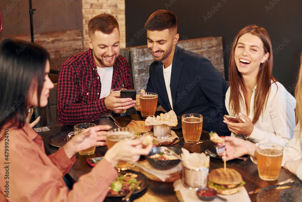 Weekend leisure. Group of young friends sitting together in bar with beer