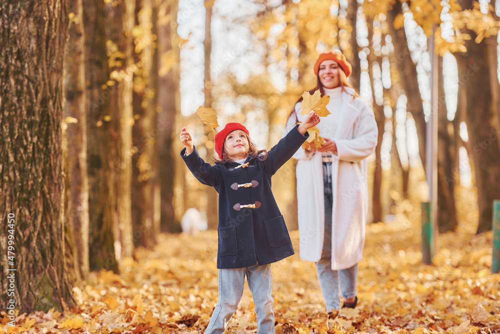 Girl is in a red beret. Mother with her little daughter is having walk in the autumn park Girl is in a red beret. Mother with her little daughter is having walk in the autumn park