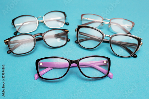 Many different glasses for vision on a blue background. Group of glasses with lenses for vision correction. Vision problems
