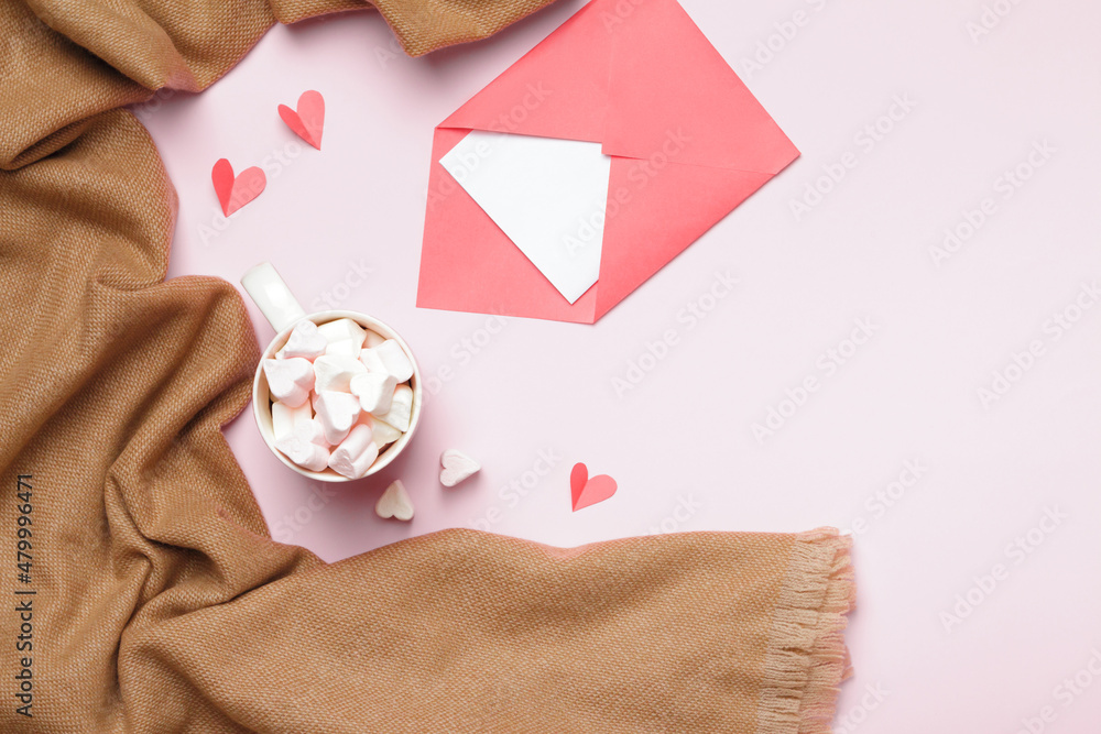 Beige cashmere scarf marshmallow cup envelope with note on pink background. Valentine's day composition.