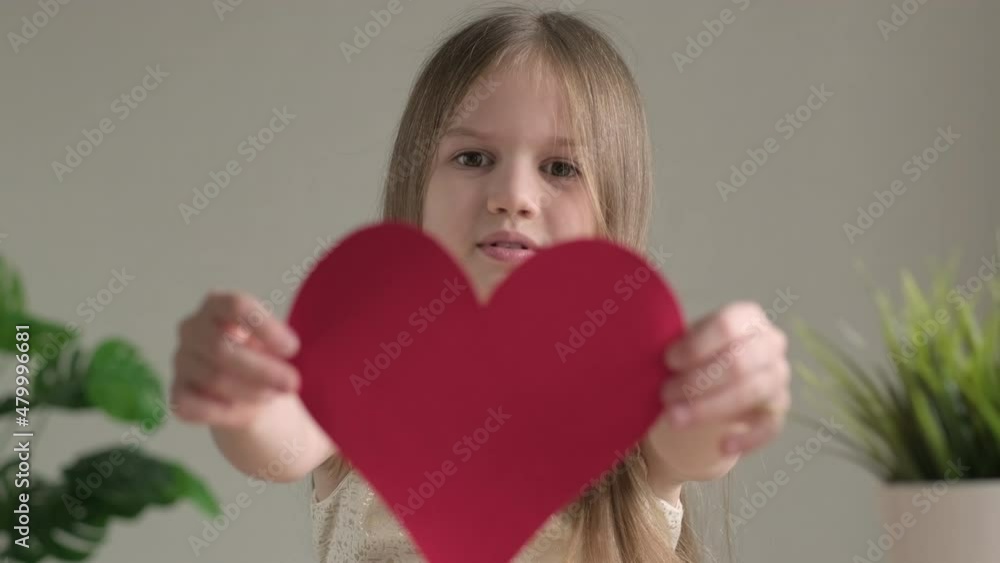 Cute little girl smiling giving handmade paper red heart. Happy child girl with present for Valentines Day, mothers or fathers day. DIY concept. Cute little girl smiling giving handmade paper red heart. Happy child girl with present for Valentines Day, mothers or fathers day. DIY concept.