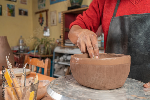 Potter molding a clay bowl with his hand in his workshop