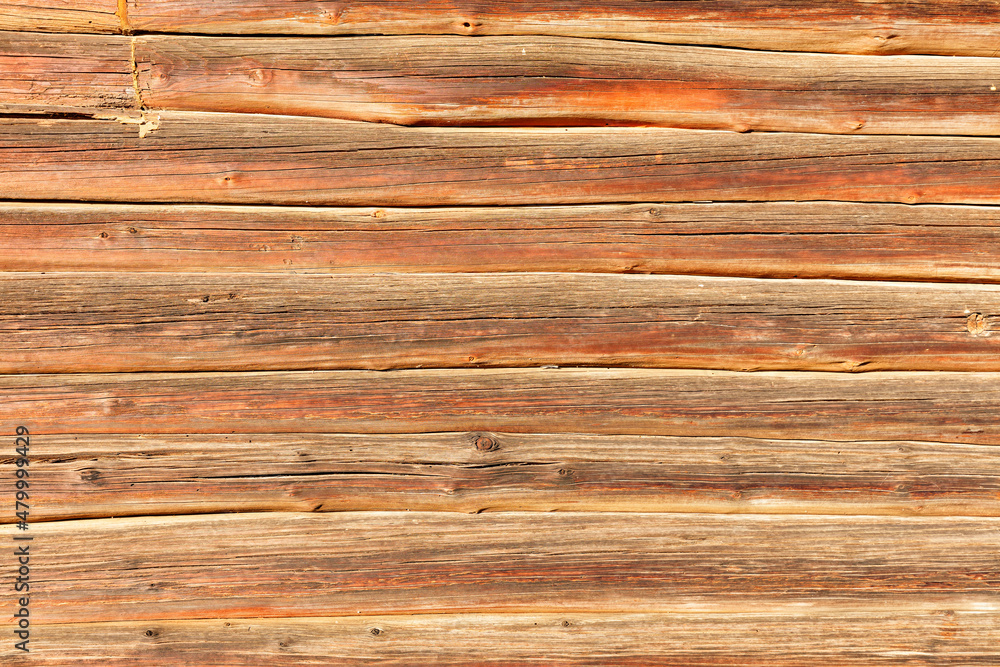 The texture of brown weathered wooden logs stacked tightly together in a bright sun. The texture of brown weathered wooden logs stacked tightly together in a bright sun.