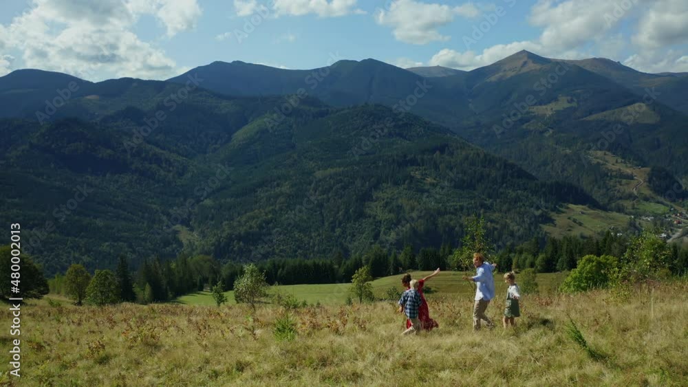 Kids parents against mountains dancing grass enjoying time blue sky background Kids parents against mountains dancing grass enjoying time blue sky background