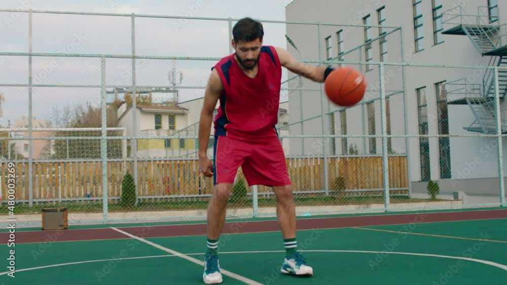 Large basketball court in front of the camera man in red sport suit playing concentrated with a ball Large basketball court in front of the camera man in red sport suit playing concentrated with a ball