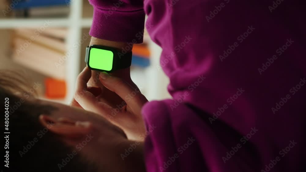 Vertical video of man using smartwatch with chroma key close-up. Young guy sitting on sofa and wearing fitness bracelet with green screen, back view. Vertical video of man using smartwatch with chroma key close-up. Young guy sitting on sofa and wearing fitness bracelet with green screen, back view.