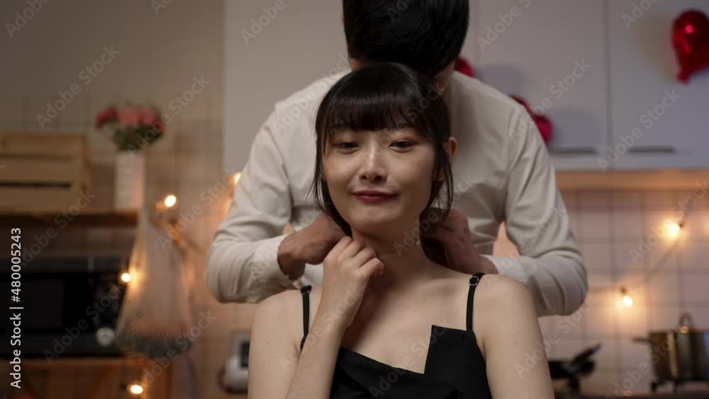 closeup view of a smiling female wearing black dress kissing her husband, feeling happy about getting gift necklace on valentine’s day at home closeup view of a smiling female wearing black dress kissing her husband, feeling happy about getting gift necklace on valentine’s day at home