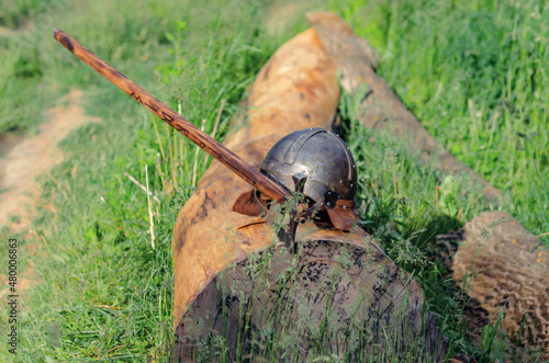 View of ancient Viking armor lying on a wooden log. Helmet and ax. Historical photo concept.