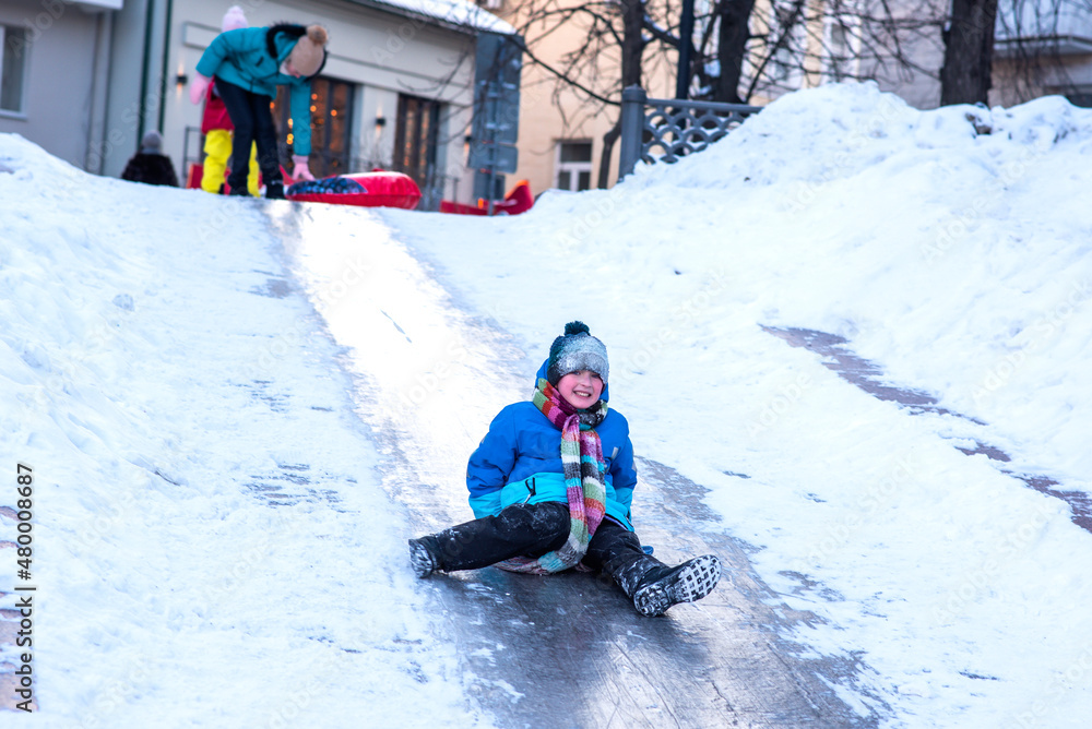little boy rides an ice slide in the city. child in blue clothes having fun and resting on winter holidays in the city
little boy rides an ice slide in the city. child in blue clothes having fun and resting on winter holidays in the city