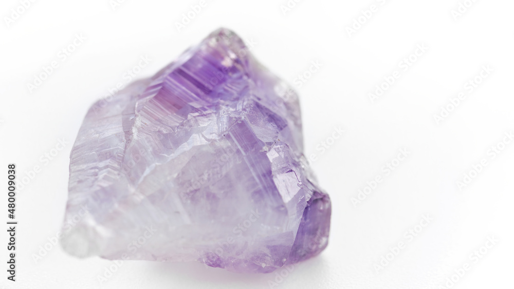 Fototapeta premium Amethyst macro photography. Purple translucent stone on a white background. Massage of the face and body with gems. The use of minerals and semi-precious stones in the practice of alternative medicine
