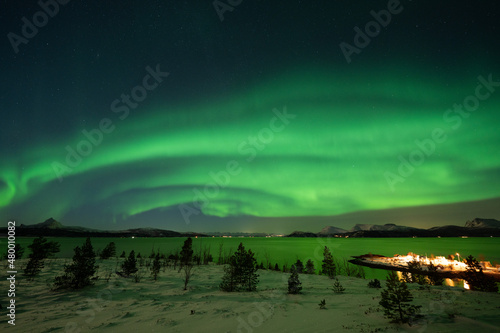 Aurora Borealis over norwegian fjord reflecting green color
