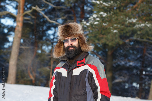 Winter portrait of a bearded man in a pine forest.