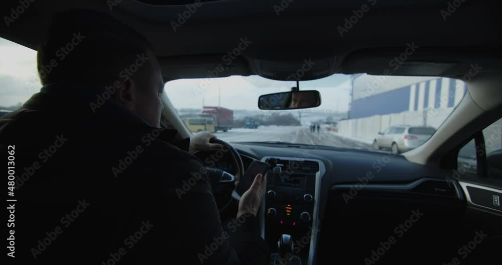 In the car, the man behind the wheel is talking on the phone, moving snowy road In the car, the man behind the wheel is talking on the phone, moving snowy road