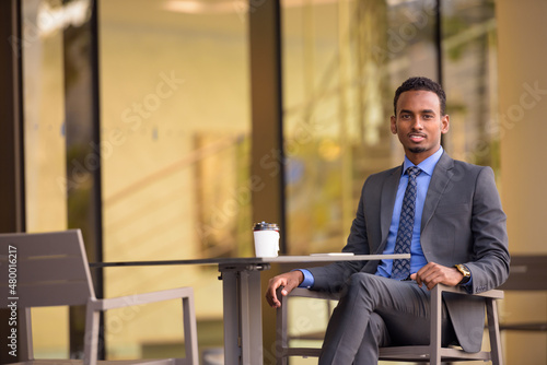 Handsome young black businessman relaxing at coffee shop restaurant outdoors