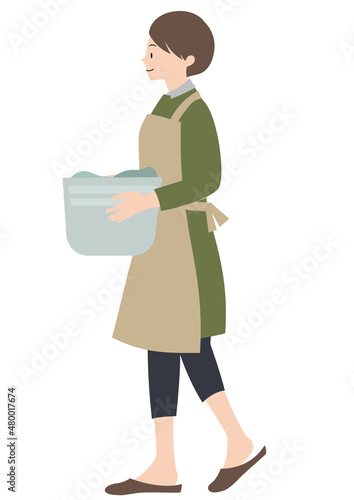 イラスト素材：エプロンをして笑顔で洗濯物を運ぶ女性（家事代行・家事分担等のイメージに）