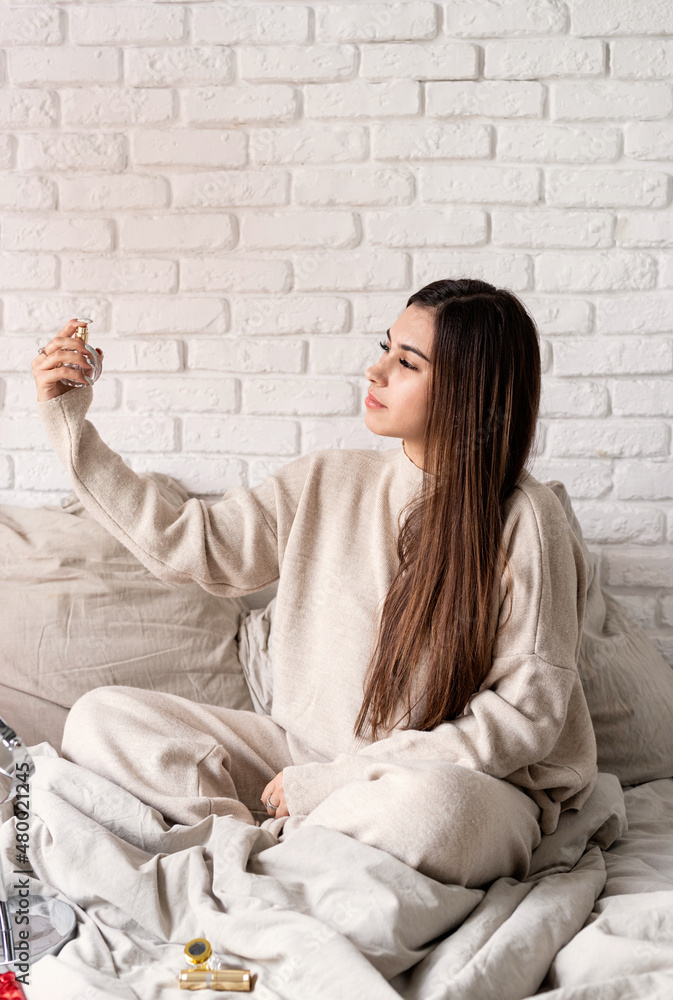 Young brunette woman sitting in the bed making up Young brunette woman sitting in the bed making up