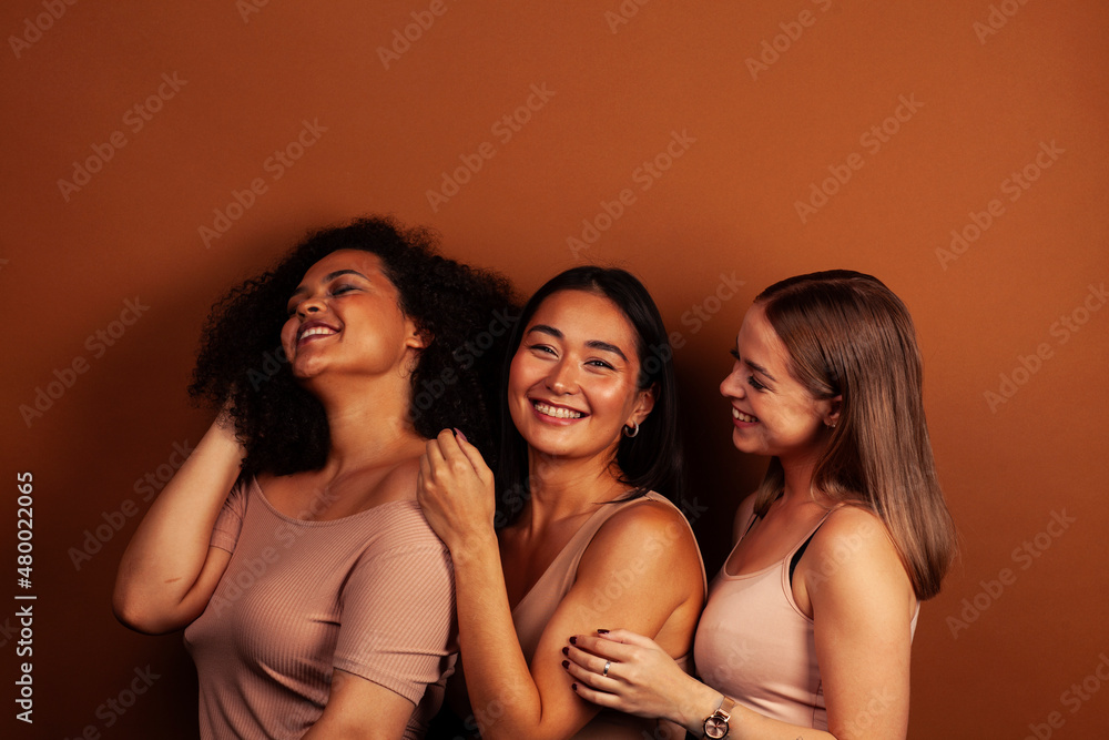 Obraz premium young pretty asian, caucasian, african woman posing cheerful together on brown background, lifestyle diverse nationality people concept