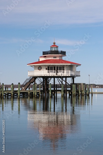 Lighthouse Cambridge Maryland sits over Choptank river in Chesapeake bay with reflection.  Screwpile construction, round form.  Welcoming iconic lighthouse beacons over water guiding sailing vessels.  photo