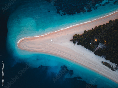 Fototapeta Naklejka Na Ścianę i Meble -  Top down view of famous Zlatni rat beach in Bol at night, first lights are on, Island Brac, Croatia, Europe. Also called golden horn or golden cape. April, 2021.