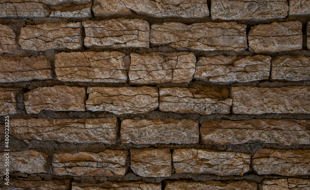 Obraz premium Old brown stone wall. Stone wall texture. Old bricks in old medieval wall. Exterior historical building. Village rural background. Graphic texture element.
