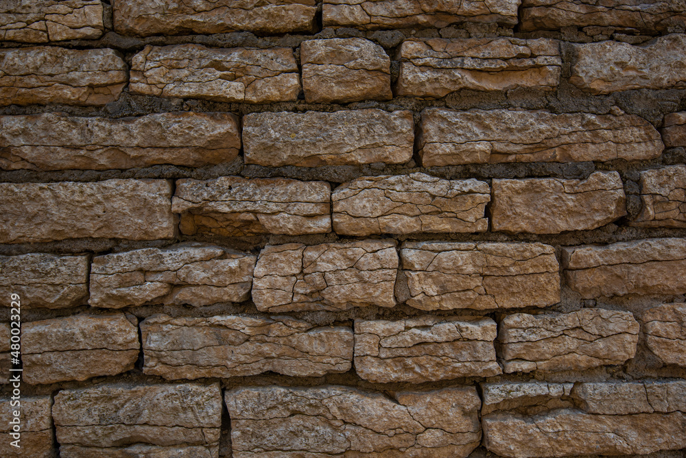 Old brown stone wall. Stone wall texture. Old bricks in old medieval wall. Exterior historical building. Village rural background. Graphic texture element.