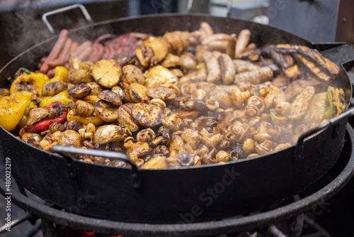 meat and potatoes in a large cauldron at the fair. street fast food