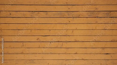 Vintage wood background. Old weathered wooden plank painted in yellow color. Boards with cracked and peeling paint. Old painted wood wall - texture or background.