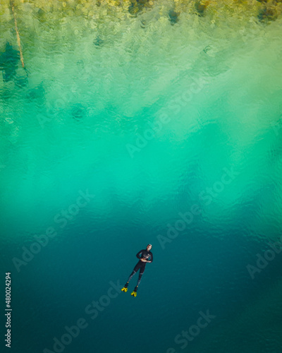 One guy snorkeling in the blue hole Izvor Cetine, Dalmatia. Aerial top down shot in April, 2021.