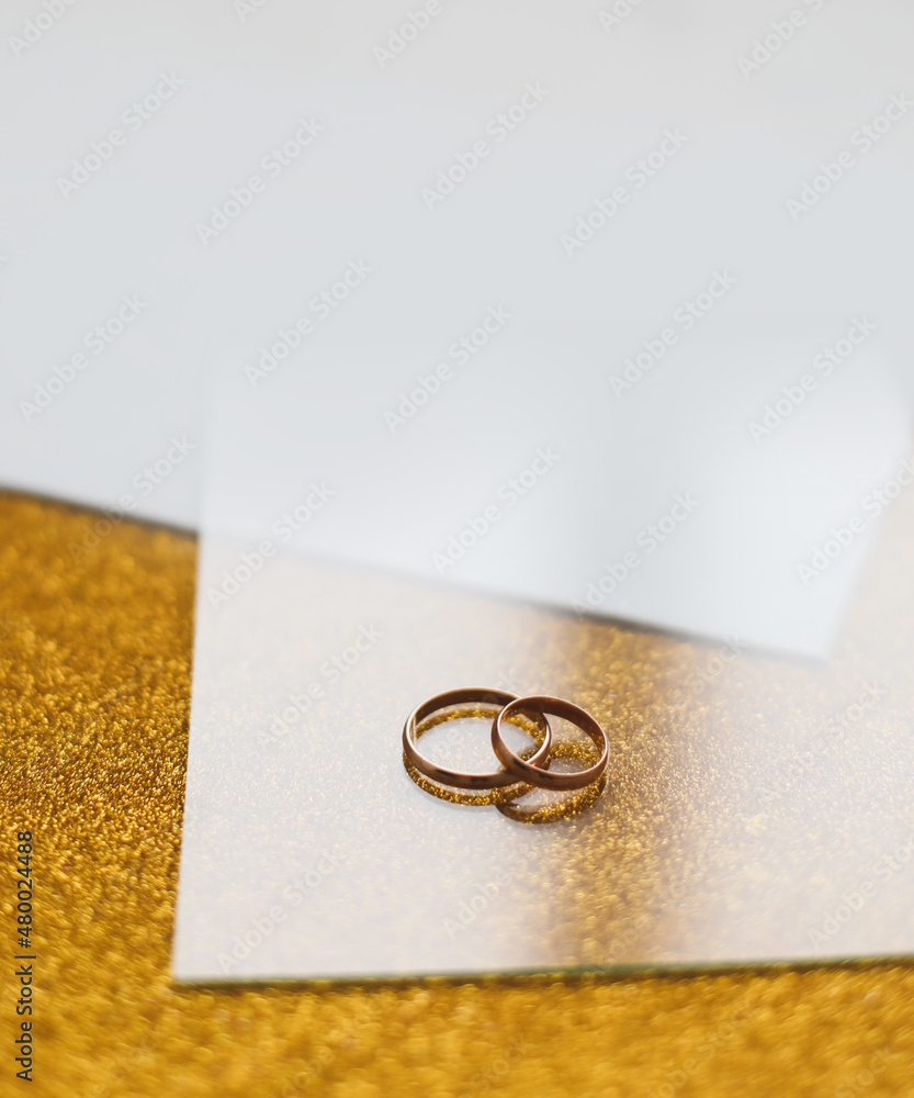 Two golden wedding rings on a golden background. Wedding invitation. valentine gift, sale shopping banner template, copy space Two golden wedding rings on a golden background. Wedding invitation. valentine gift, sale shopping banner template, copy space