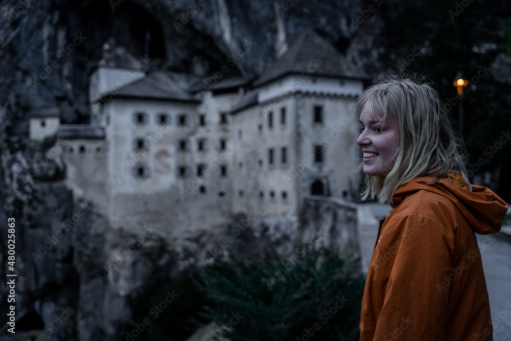 Young female girl, women laughing in front of Predjama castle - Predjamski grad in spring, Slovenia