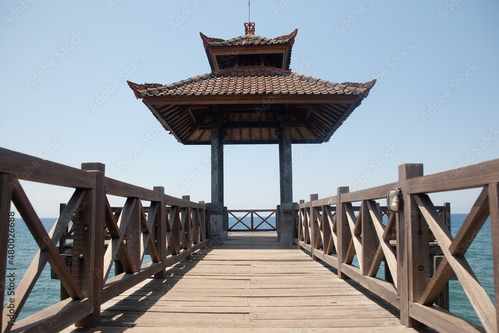 Wooden bridge with a gazebo by the sea. Rest area by the sea. Wooden structure for tourists, Bali, Indonesia.