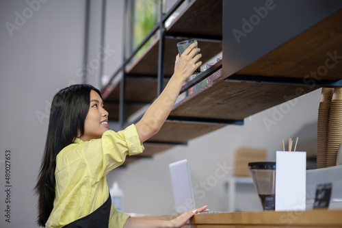 Asian young woman writing menu on a board in a cafe