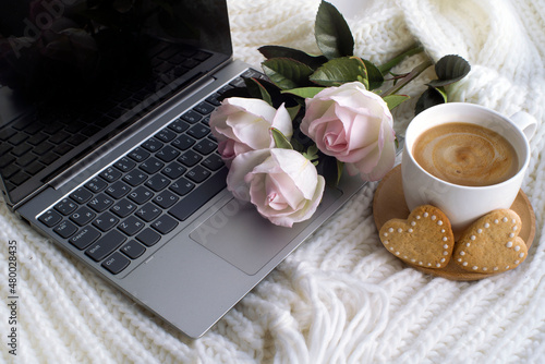 laptop, cup of coffee, bouquet of pink roses, heart shaped cookies. romantic background, valentine's day card. congratulations on March 8. cozy scene. with love.