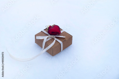 gift box and red glass heart on the snow. valentine's day card