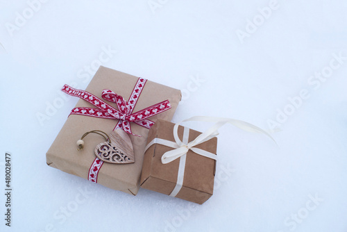 gift boxes tied with ribbons in the snow. valentine's day card, gift in love, romantic background.