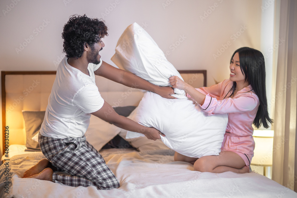 Man and woman doing pillow fight on bed Man and woman doing pillow fight on bed