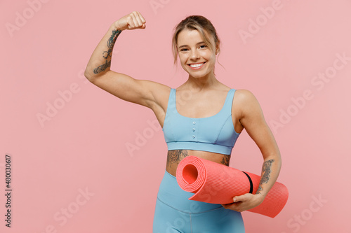 Foto Young strong sporty athletic fitness trainer instructor woman wear blue tracksuit spend time in home gym show hand biceps muscles isolated on pastel plain light pink background