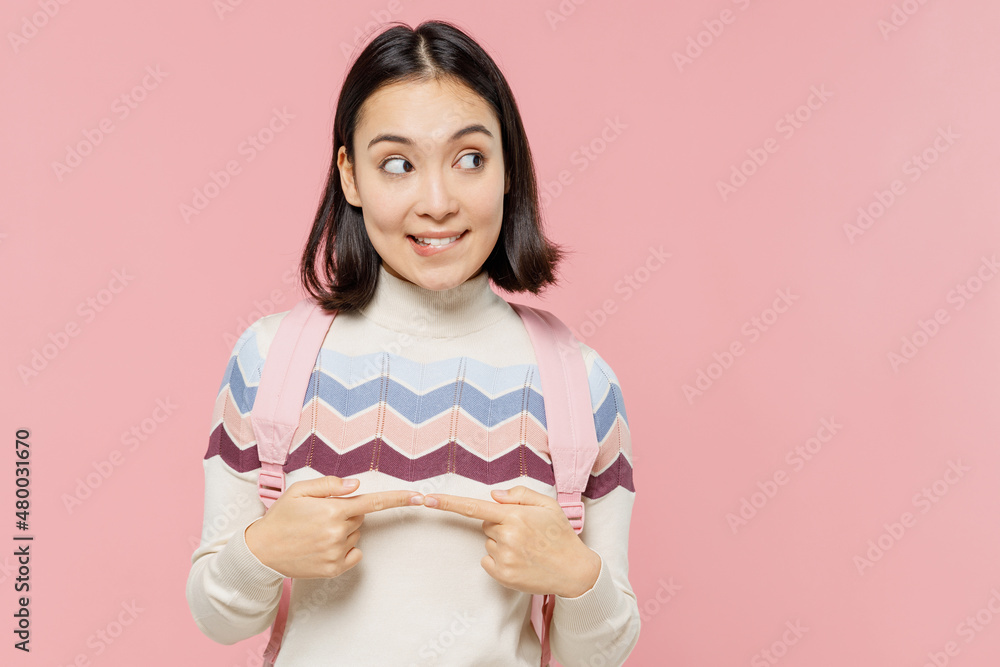 Minded teen student girl of Asian ethnicity in sweater backpack hold books look aside on workspace area mock up isolated on pastel plain light pink background Education in university college concept Minded teen student girl of Asian ethnicity in sweater backpack hold books look aside on workspace area mock up isolated on pastel plain light pink background Education in university college concept