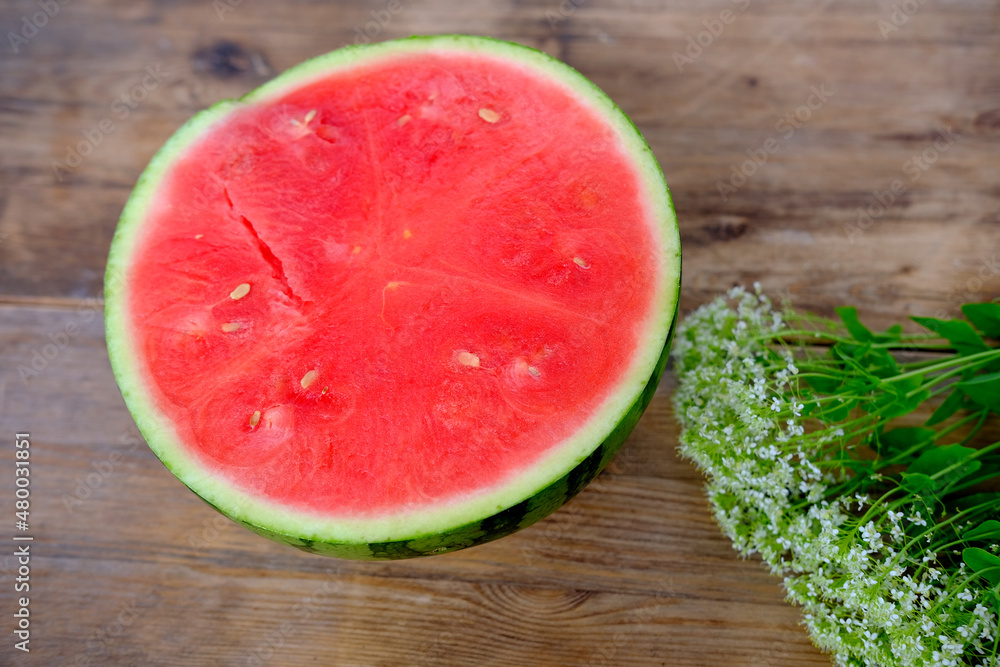 ripe red watermelon, cut in half, home cooking concept, white wildflowers, wooden table, texture of natural background, delicious summer food concept ripe red watermelon, cut in half, home cooking concept, white wildflowers, wooden table, texture of natural background, delicious summer food concept