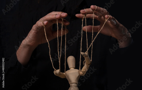 Hands manipulating wood puppet. Master of marionette.