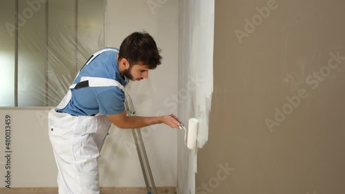 handsome young man professional painter in construction site wall painting renovation in a client house
