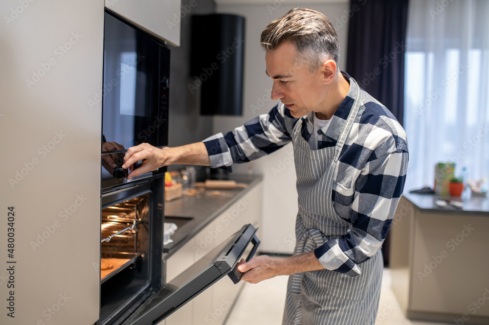 Man closing oven turning on regulating temperature Man closing oven turning on regulating temperature