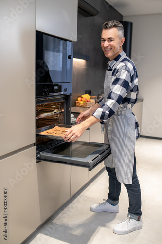 Man putting pan in oven looking at camera