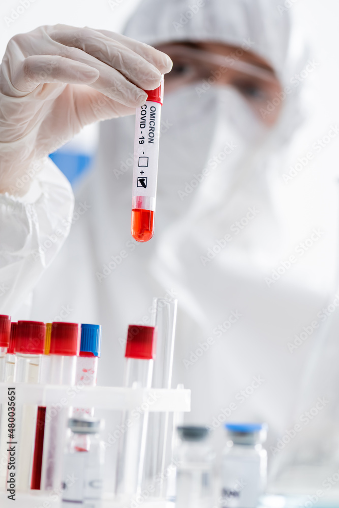 blurred scientist holding positive covid-19 omicron test while working in laboratory. blurred scientist holding positive covid-19 omicron test while working in laboratory.