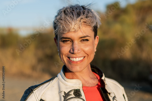 Tableau sur toile portrait of smiling young woman with blonde modern short haircut and earrings on