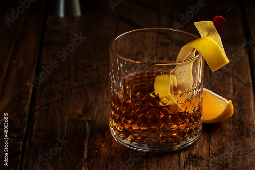 Sazerac cocktail with cognac, bourbon, absinthe, bitters, sugar and lemon zest. Old wooden bar counter background with copy space photo