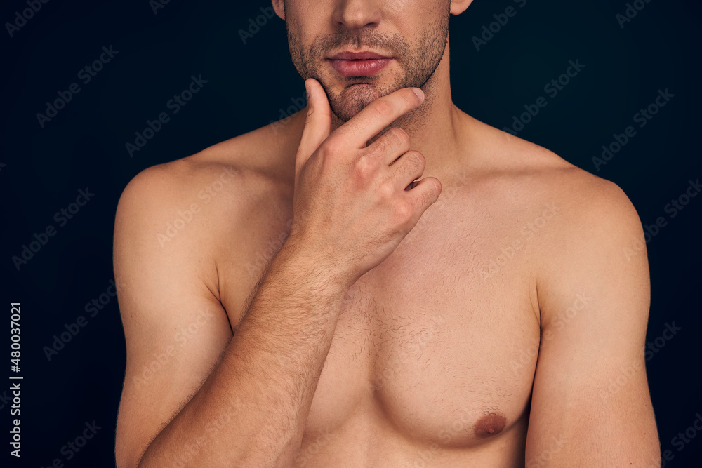 Handsome young man isolated. Cropped image of shirtless muscular man is standing on dark blue background. Handsome young man isolated. Cropped image of shirtless muscular man is standing on dark blue background.